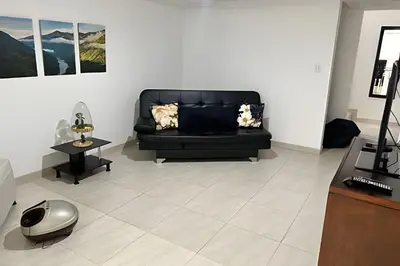 a living room with a black couch and a table at Casa Acogedora y Amplia - Estrato 5 in Manizales