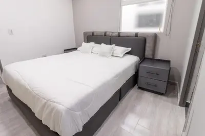 a bedroom with a large bed with white sheets and a window at Charming scape cozy and stylish N Medellin in Medellín
