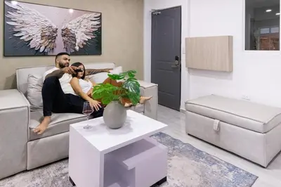 a man and woman sitting on a couch in a living room at Charming scape cozy and stylish N Medellin in Medellín