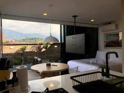 a bedroom with a bed and a balcony with a table at Cozy Studio in Laureles MDE in Medellín