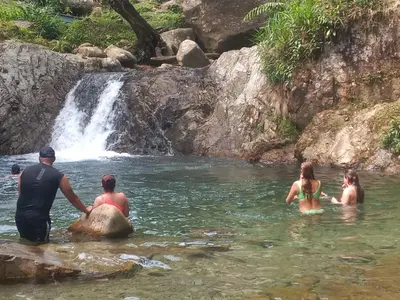 a group of people in the water near a waterfall at Glasshouse with river in San Rafael