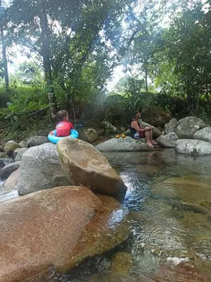 two people sitting on rocks next to a river at Glasshouse with river in San Rafael