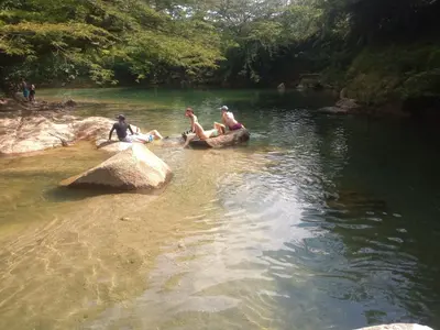 a group of people sitting on rocks in a river at Cabin with River in San Rafael