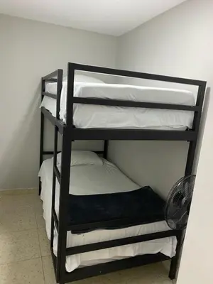 a black bunk bed with white sheets and a fan at Hotel Don Pacho in Los Andes