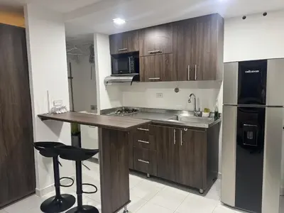 a kitchen with wooden cabinets and a sink and a refrigerator at Gran loft cerca al tesoro y al lleras 121 in Medellín