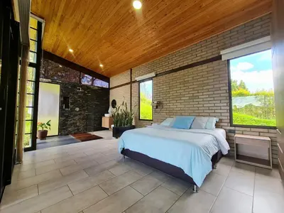a bedroom with a bed and a brick wall at Los Pinos in Guatapé