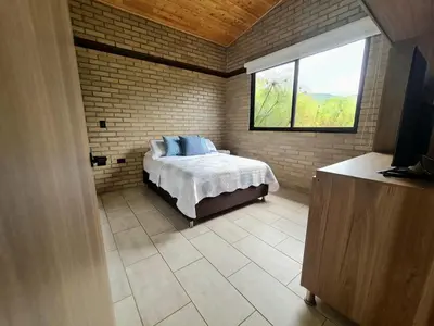 a bedroom with a bed in a room with a window at Los Pinos in Guatapé