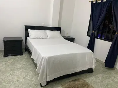a bedroom with a large white bed and a window at Apartamento a 5 minuto de hacienda napoles y el santorine colombiano in Doradal