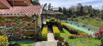 a house with a garden with flowers and a pathway at Finca Con Hermosa Vista a la Piedra del Peñol y Jacuzzi Grande in El Peñol