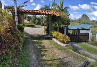 a gate to a house with a lake in the background at Finca Con Hermosa Vista a la Piedra del Peñol y Jacuzzi Grande in El Peñol