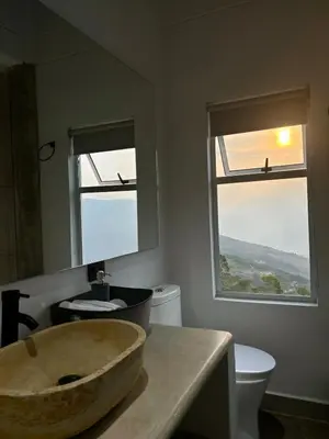 a bathroom with a large stone sink and two windows at Villa Entre Nubes in El Hatillo