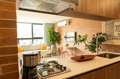 a kitchen with a stove top oven next to a living room at Nuevo y cálido Loft en Laureles in Medellín