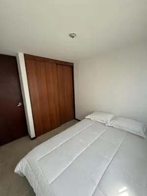 a bedroom with a large white bed and a wooden door at Apartment in Poblado 17th Floor W Pool in Medellín