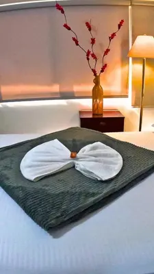a white shirt and a vase on a bed at Hotel Marinilla Oriente in Marinilla