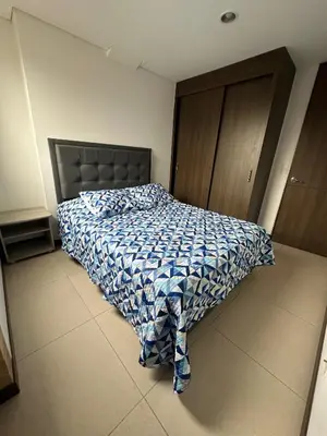a bedroom with a bed with a blue and white comforter at Confortable Apartamento, Sabaneta in Sabaneta