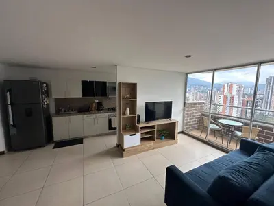a living room with a blue couch and a large window at Confortable Apartamento, Sabaneta in Sabaneta