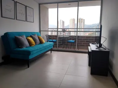 a living room with a blue couch and a large window at Confortable Apartamento, Sabaneta in Sabaneta