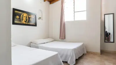 two beds in a white room with a window at Apartamento cerca a Estadio con balcon y 5 habitaciones in Medellín