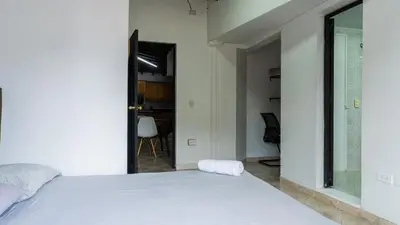 a bedroom with a white bed and a window at Apartamento cerca a Estadio con balcon y 5 habitaciones in Medellín