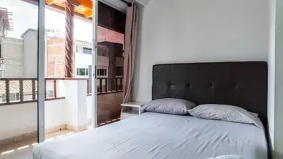 a bedroom with a bed and a large window at Apartamento cerca a Estadio con balcon y 5 habitaciones in Medellín