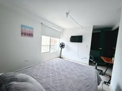 a bedroom with a bed and a desk and a window at Apartamento cerca a Estadio con balcon y 5 habitaciones in Medellín