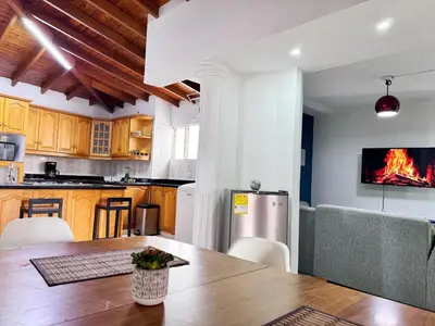 a kitchen and dining room with a table and a fireplace at Apartamento cerca a Estadio con balcon y 5 habitaciones in Medellín