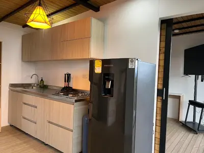 a kitchen with a stainless steel refrigerator and wooden cabinets at Althuum House in Chiquinquirá