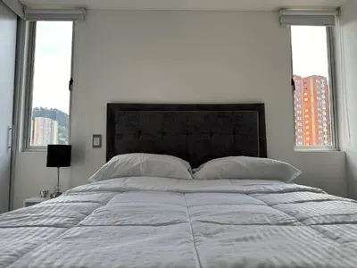 a bedroom with a large white bed with two windows at Apartamento Las Vegas Plaza in Sabaneta