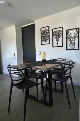 a dining room table with two chairs and paintings on the wall at Apartamento Las Vegas Plaza in Sabaneta