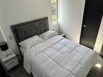 a bedroom with a large white bed with a window at Apartamento Las Vegas Plaza in Sabaneta