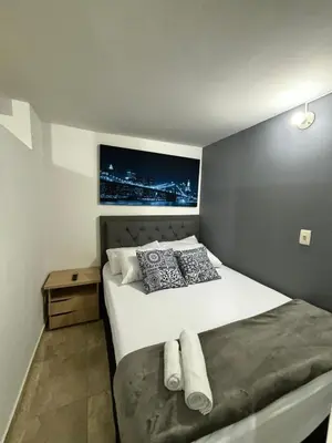 a bedroom with a large white bed with a wall at Apartamentos Bello Antioquia in Bello