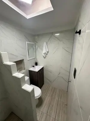 a white bathroom with a toilet and a shower at LA CASONA Finca Hostal in Apía