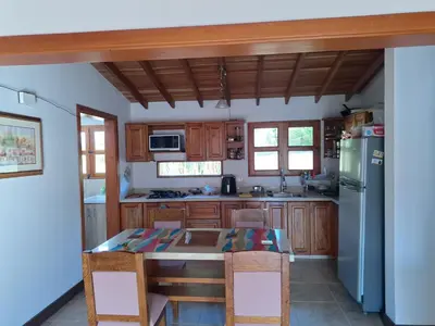 a kitchen with a table and a refrigerator at Habitación en Casa San Miguel, Vereda El Plan, Santa Elena in Medellín