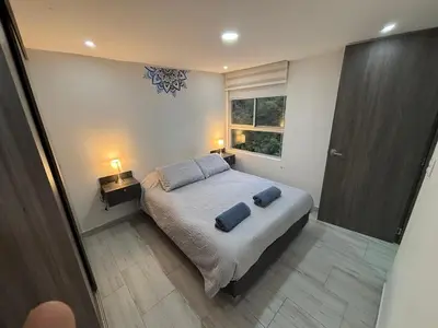 a bedroom with a bed with two blue towels on it at Apto nuevo, tranquilo y central in Manizales