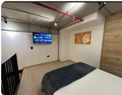 a room with a bed and a tv on the wall at Hermoso Loft in Medellín
