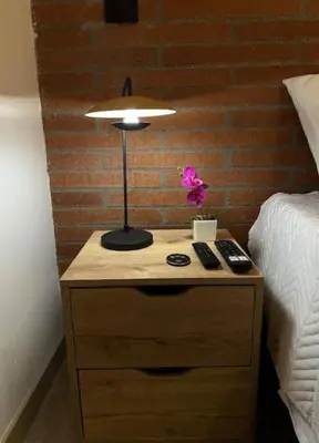 a lamp on a night stand next to a bed at Hermoso Loft in Medellín