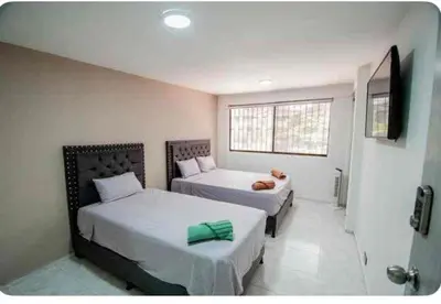 a bedroom with two beds and a flat screen tv at Hotel Boutique Casa Teresita in Medellín