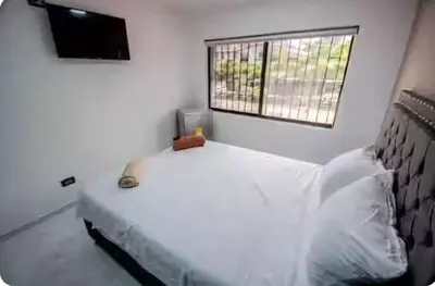 a white bedroom with a bed and a window at Hotel Boutique Casa Teresita in Medellín