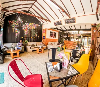 a room with chairs and tables and a man sitting on a couch at Panela Hostel Poblado in Medellín