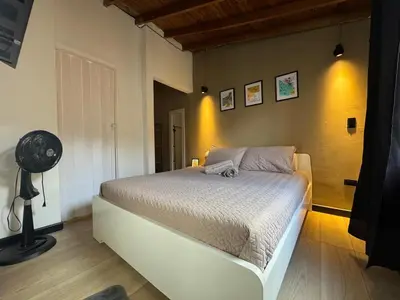 a bedroom with a white bed and a fan at Lucia Metro House in Medellín