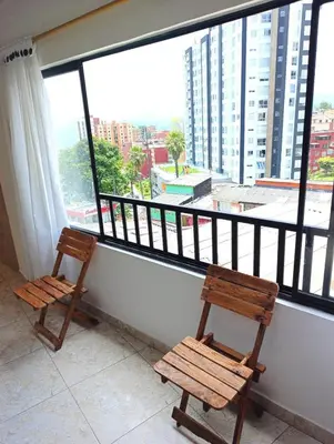 two wooden chairs sitting in front of a large window at Agradable y comodo apartamento en Manizales, barrio Chipre in Manizales