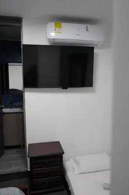 a small bedroom with a bed and a tv on the wall at Hotel Serymar la 70 in Medellín