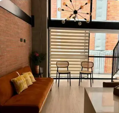 a living room with a couch and chairs and a clock at Loft hermoso y céntrico 1109 in Medellín