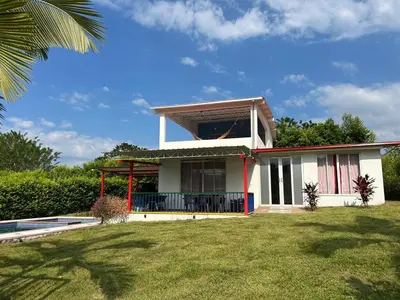 a small white house with a lawn in front of it at Casa Campestre La Mesita in Palestina