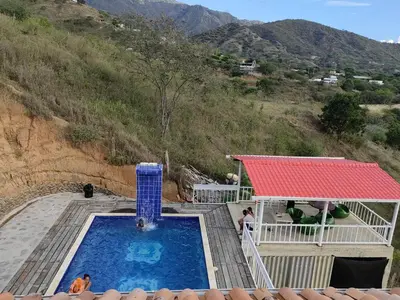 a swimming pool with a red roof and a mountain at Finca de Rubén in Olaya