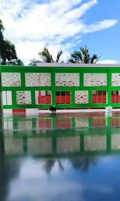 a green building with red windows and palm trees at La Casa del Colibrí in Jericó