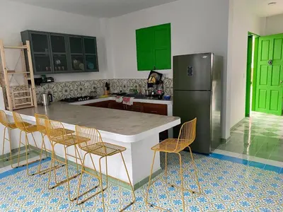 a kitchen with green cabinets and a kitchen island with chairs at La Casa del Colibrí in Jericó