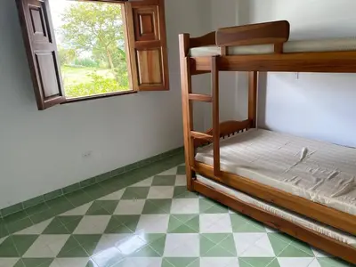 a bedroom with bunk beds with a window and a tiled floor at La Casa del Colibrí in Jericó