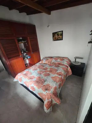 a bedroom with a bed with a floral bedspread at comoda habitacion con baño compartido in Itagüí