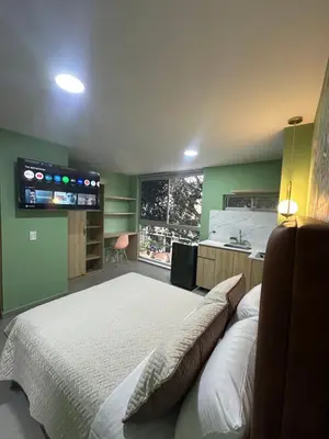 a bedroom with a large bed and a kitchen at Amaranto Suites in Medellín